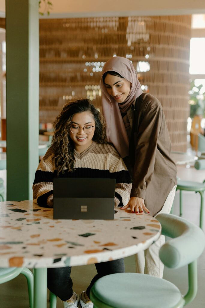 Two friends overlooking a laptop screen smiling